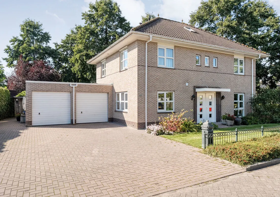 Voorgevel van De Veurdele 58 met dubbele garage, oprit en voortuin